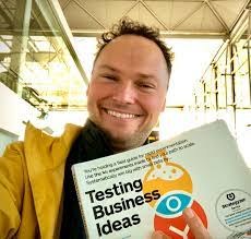 Andreas Conradi holding up a copy of &lsquo;Testing Business Ideas&rsquo; at an airport.