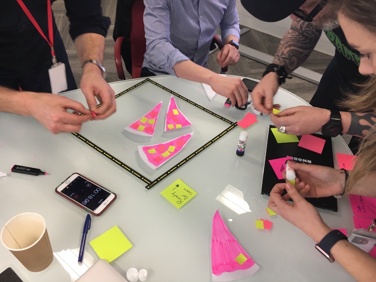 A cross-functional team prototyping with paper and sticky notes against a timer