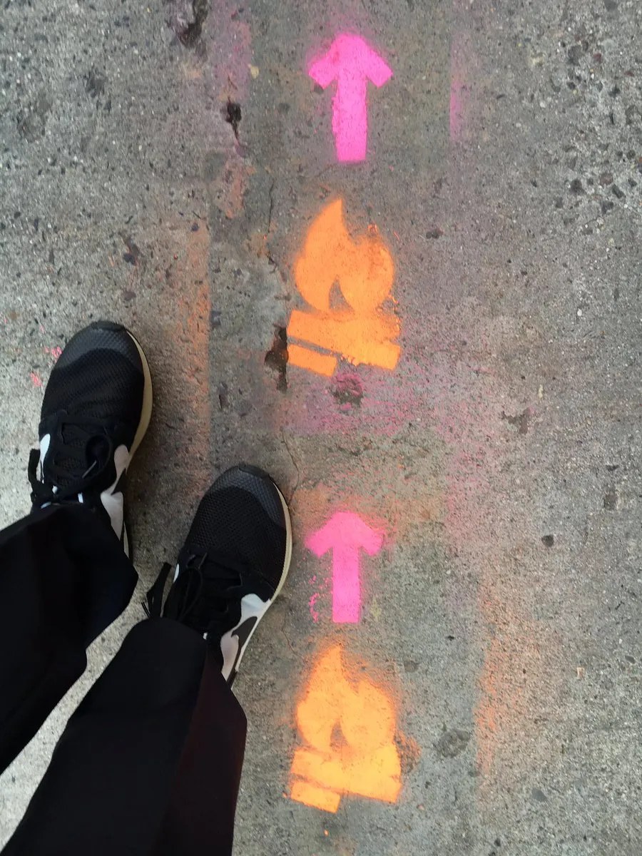 Spray-painted arrows and flame icons on a pavement, pointing the way to the venue.